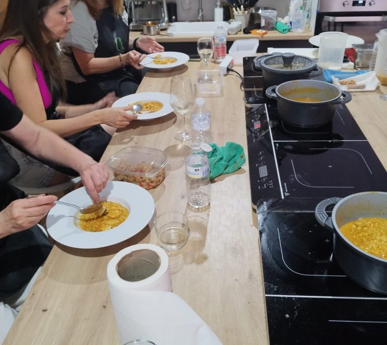 Grupo de personas cocinando y preparando ensaladas en una cocina luminosa.